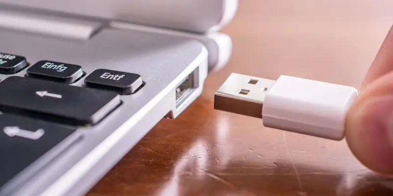 A Close-Up Image Of A Hand Connecting A Usb Cable To A Chromebook, Highlighting The Process Of Setting Up An External Webcam Via A Usb Port.